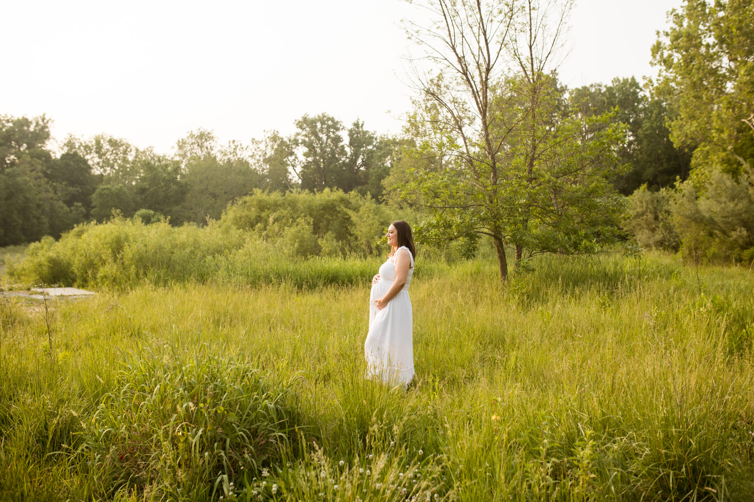 Woman in white dress pregnant in field