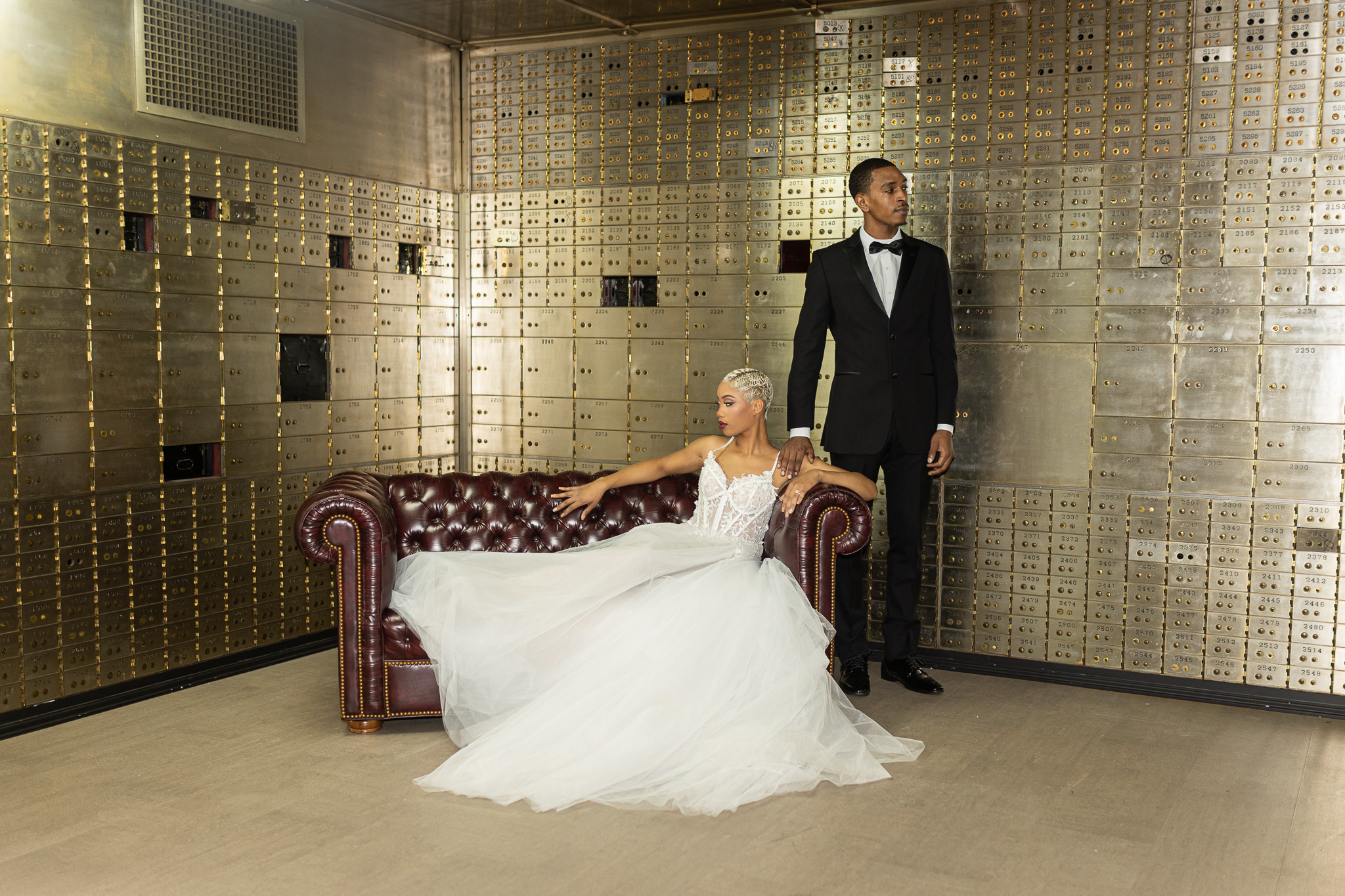 Bride sitting on couch and groom standing in vault at the Treasury wedding venue in metro Detroit MI