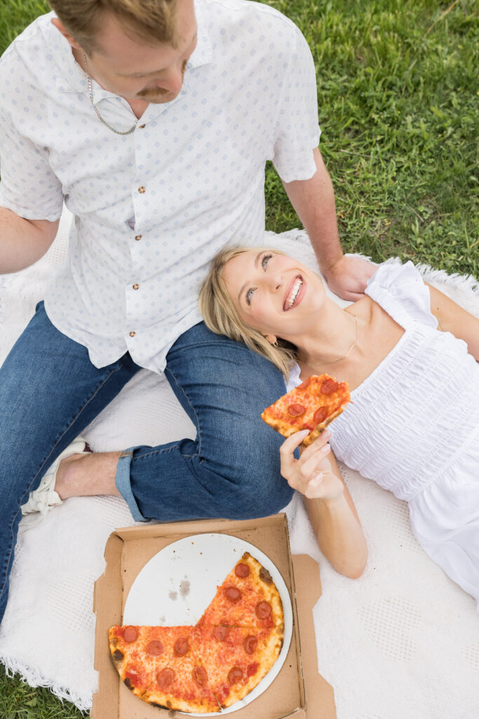 woman eating pizza lying on fiances lap during engagement photos