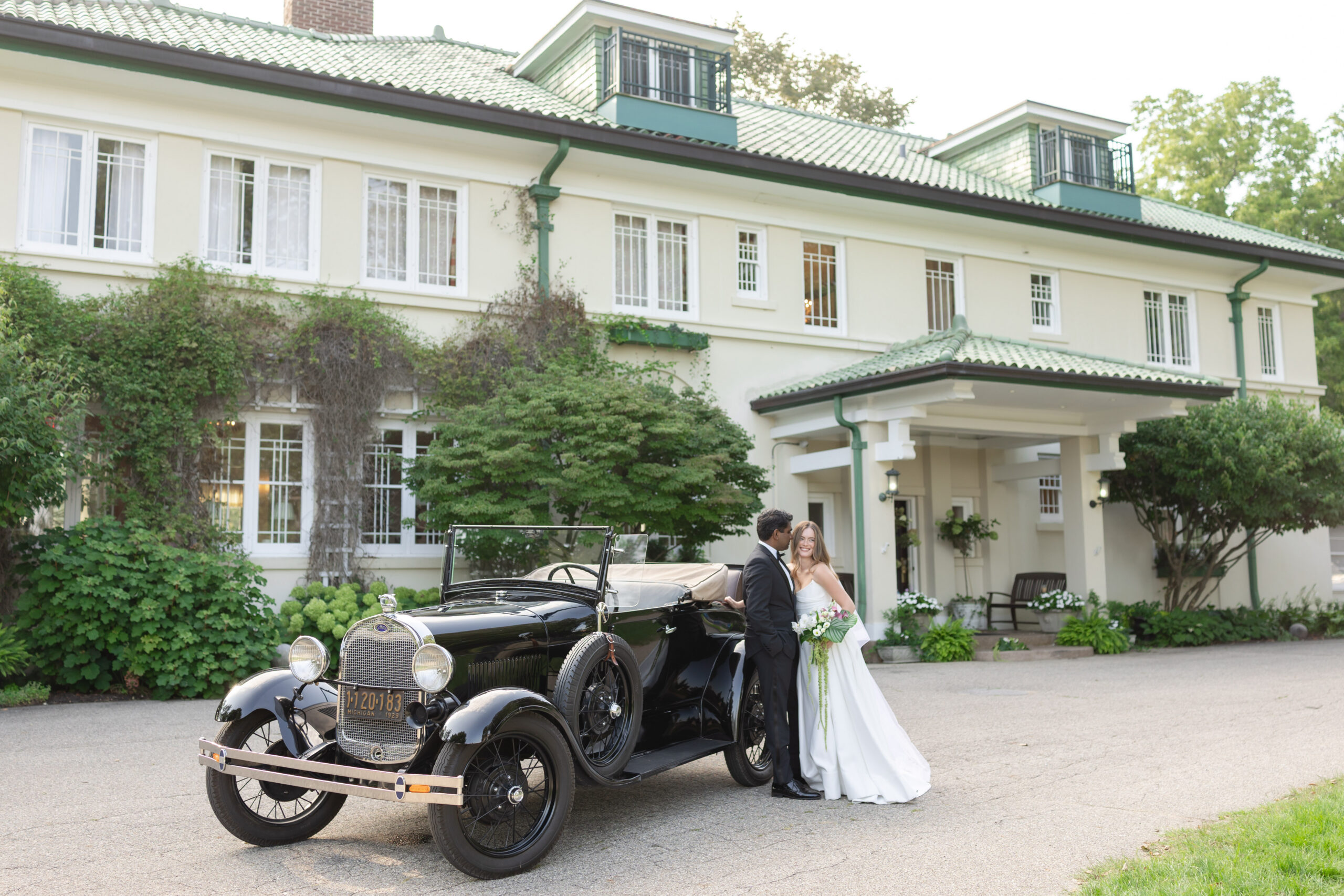 Bride and groom post near vintage car in front of Belvedere Estate Wedding Venue