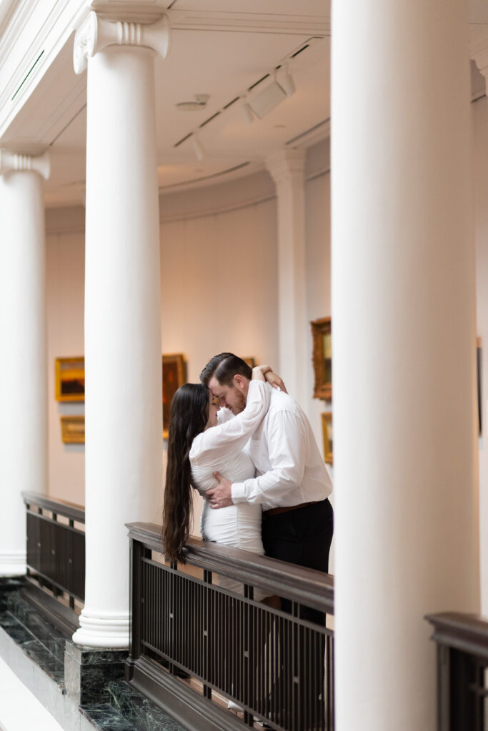 Man and woman between white pillars in art museum for Engagement phtoos