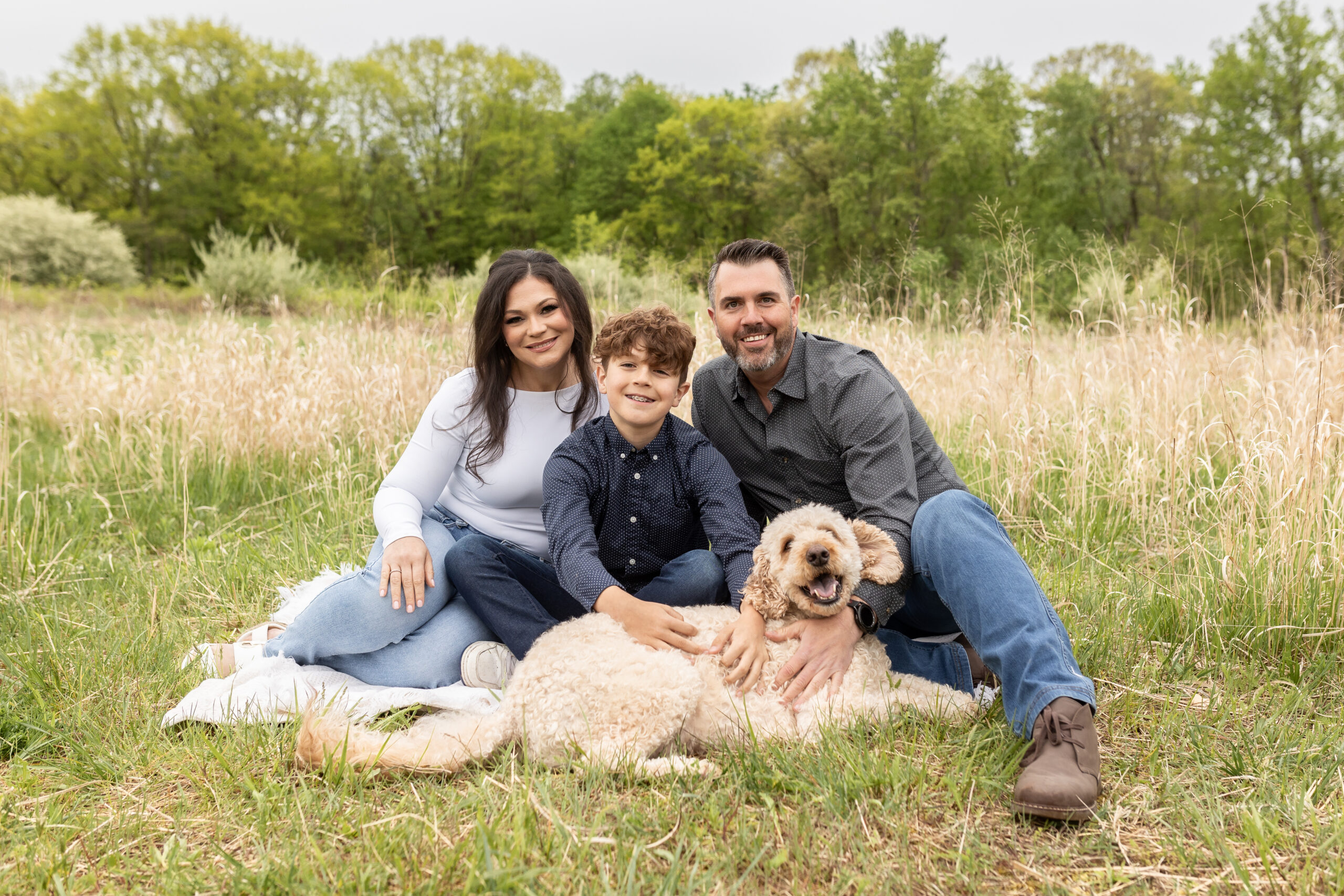Family sitting in field with dog for family photos at Stony Creek Metropark