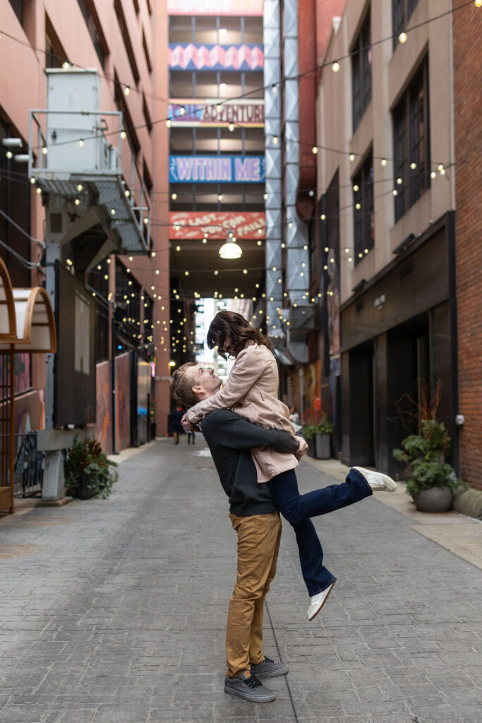 Man lifting woman in the Belt Ally during Detroit engagement photos