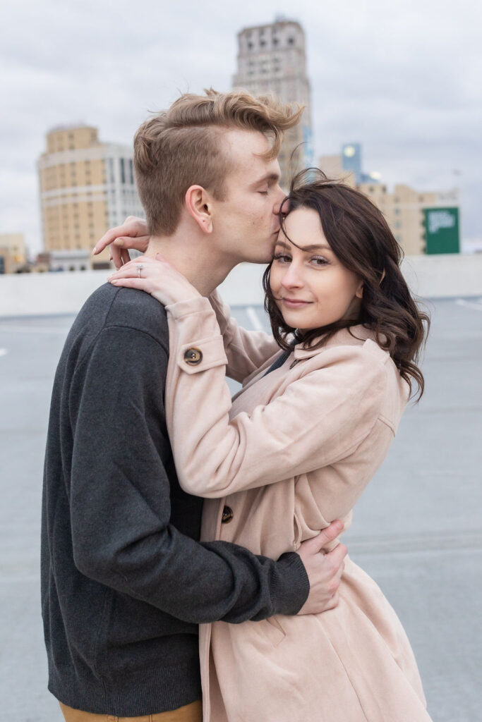 Man kissing woman on head during engagement photography in Detroit MI