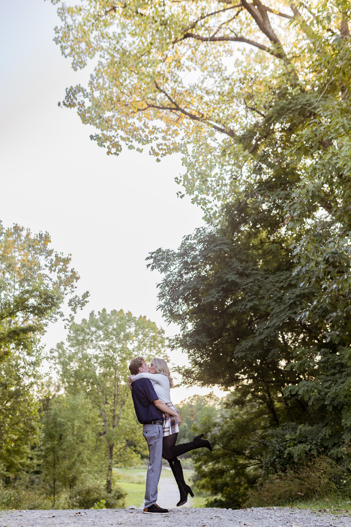 Man lifting woman during fall engagement photos in Shelby Township Michigan by Savvy Shoots Photography