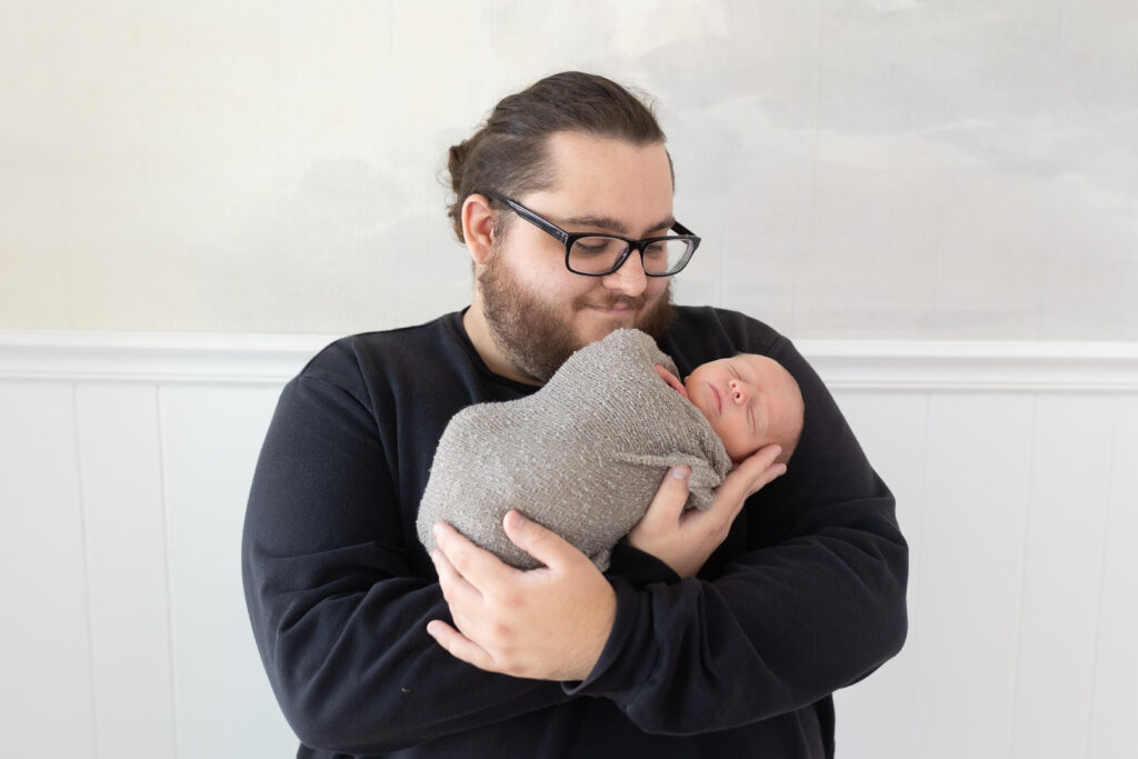 Dad holding baby during newborn photography in Royal Oak MI