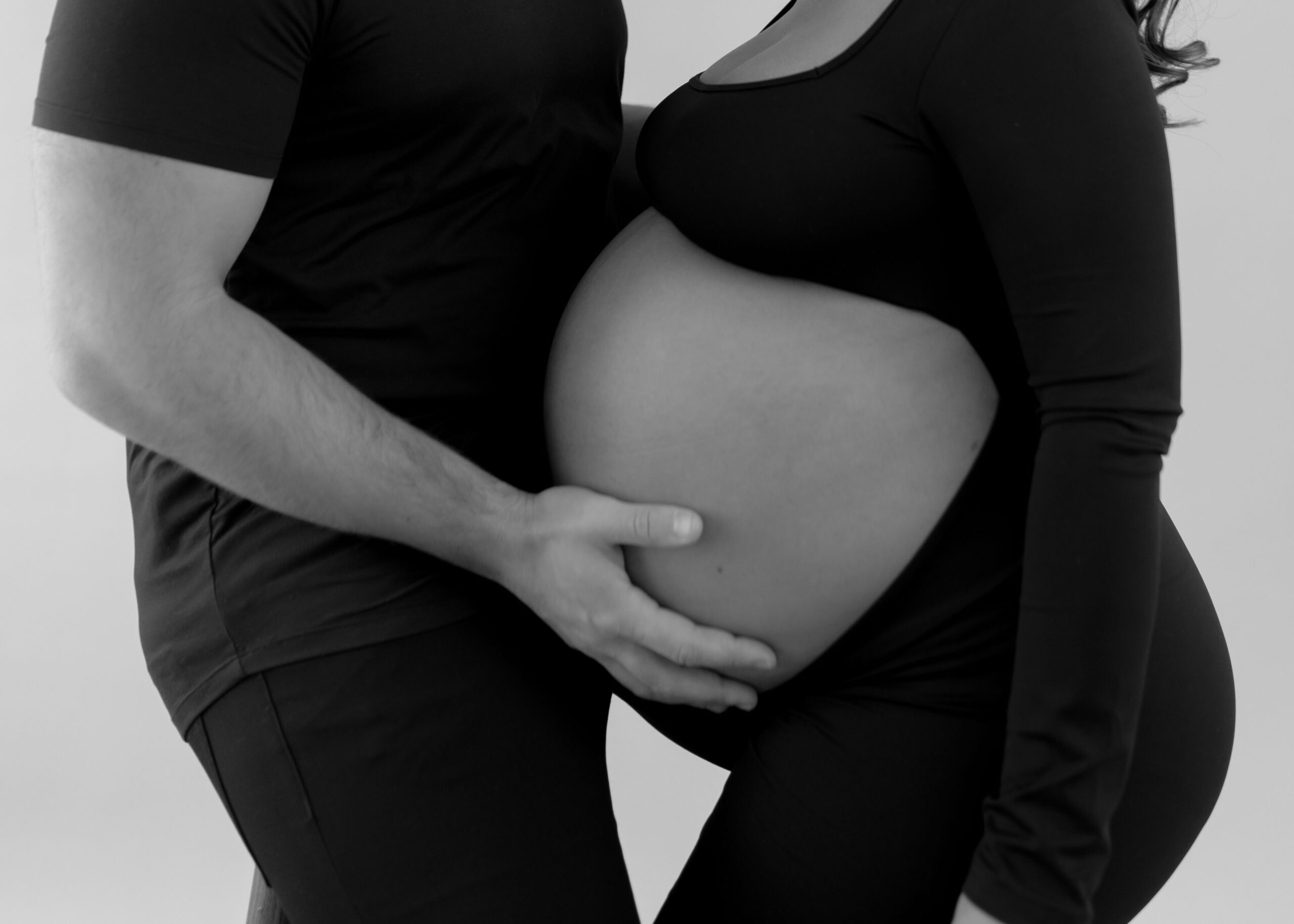 Husband and wife hands on stomach during royal oak maternity photoshoot