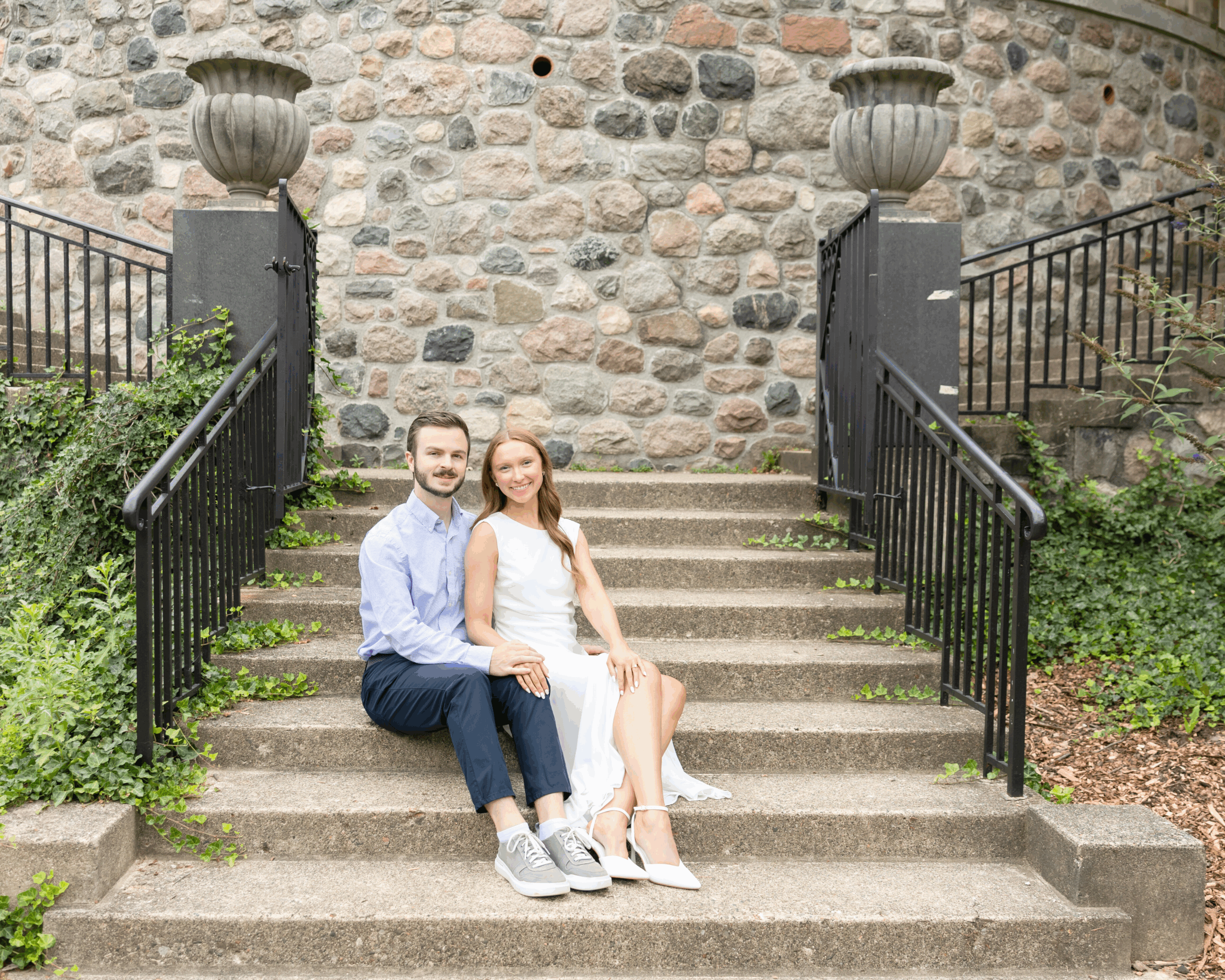 Man and woman sitting on stairs during engagement photos at Cranbrook House and Gardens