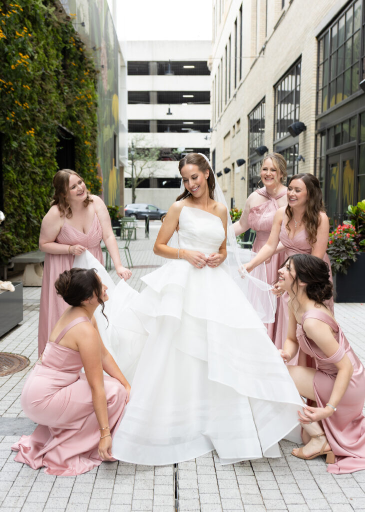 Bridemaids assisting bride with dress during Detroit wedding photography