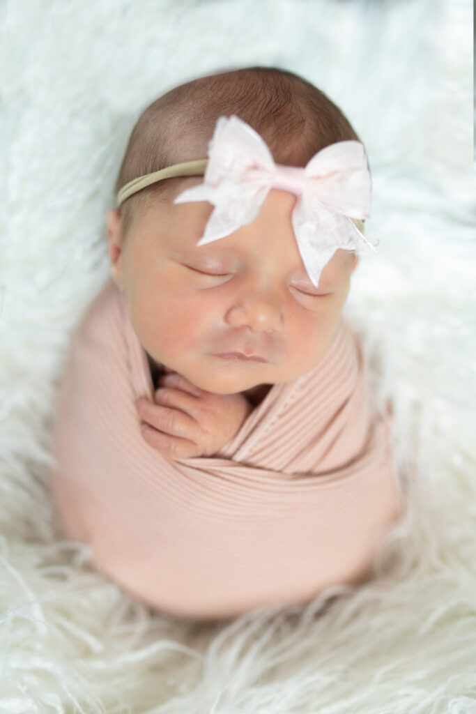 Baby wrapped in swaddle with bow for newborn photography in Oakland County MI
