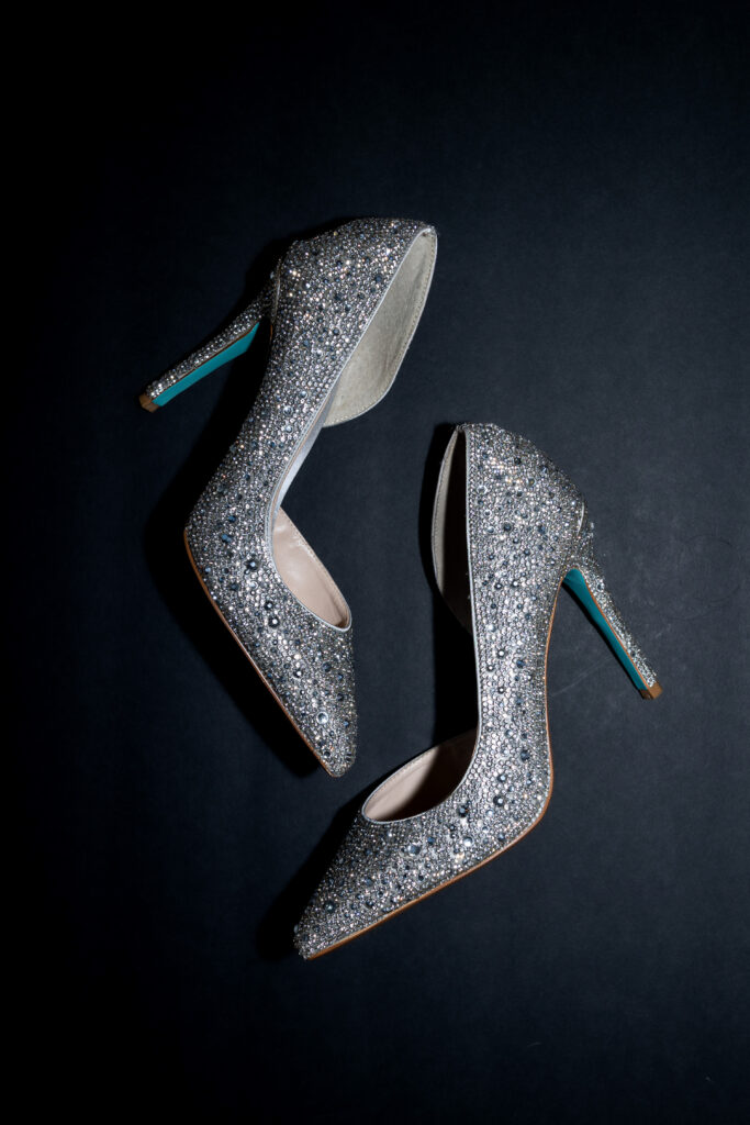 Sparkly high heels photographed against black background for wedding detail photography