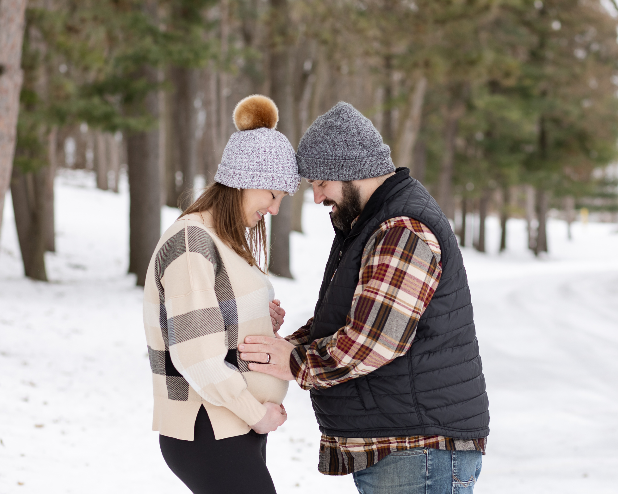 Man and woman hold woman's belly during winter maternity photos in Waterford MI
