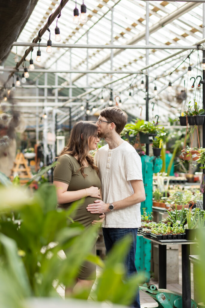 Man kissing woman on forehead during maternity photos in Oakland County MI