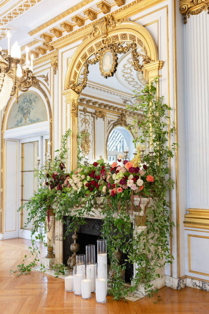 Fireplace decorated with red and pink flowers inside Philadelphia wedding venue