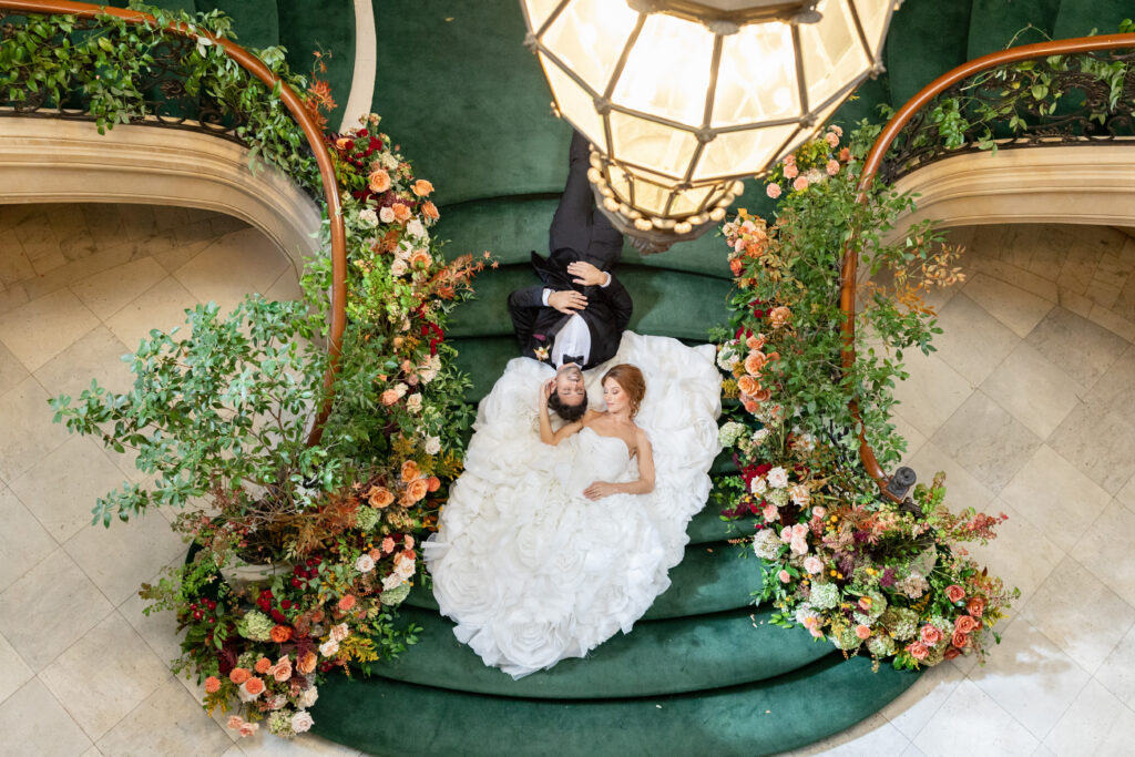 Groom and bride lay on backs on green staircase during Philadelphia wedding photography